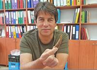 Dr. Omry Barzilai drží prehistorický kamenný nástroj nalezený v Boker Tachtit. (Israel Antiquities Authority)